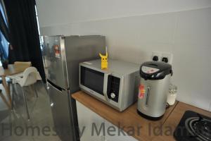 a kitchen counter with a microwave and a refrigerator at homestay mekar idaman in Kepala Batas