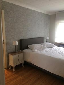 a bedroom with a large white bed and a night stand at Le Lendemain in Lovendegem