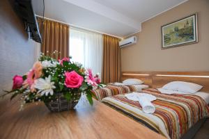 a hotel room with two beds and a vase of flowers at Hotel Djerdap in Kladovo +72 photos