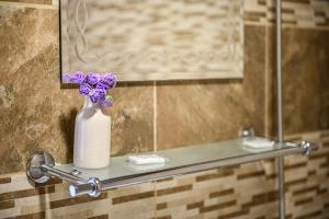 un jarrón de flores púrpuras sentado en un estante en un baño en Medi Guest House, en Sapareva Banya 34 fotos más