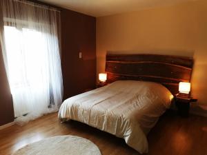 a bedroom with a bed with a wooden headboard and a window at Gîte des 3 vallées in Baume-les-Messieurs