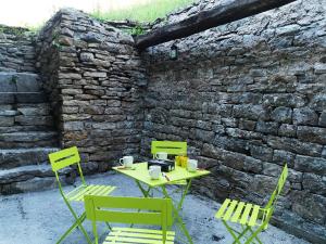 a table and two chairs and a stone wall at Gîte des 3 vallées in Baume-les-Messieurs