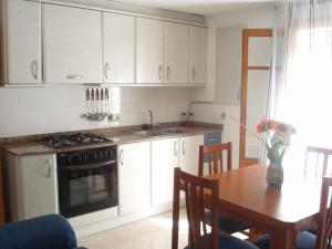 eine Küche mit weißen Schränken und einem Tisch und einem Herd in der Unterkunft APARTAMENTO NURIA GONZÁLEZ GRANDA in Peñíscola