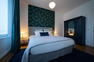 ein Schlafzimmer mit einem großen Bett und einer grünen Wand in der Unterkunft Centre ville - Appartement 3 chambres & Terrasse - La Clé des Sacres in Reims