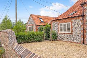 a brick house with a fence in front of it at The Sail House in Wighton