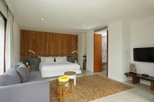 a bedroom with a bed and a couch and a tv at Aria Villas Ubud in Ubud