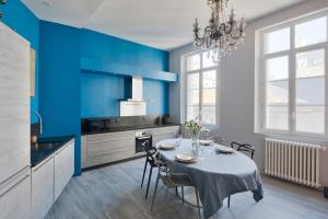 cocina con mesa y pared azul en Le Blue Note by Cocoonr - Bel appartement de standing, en Saint-Malo