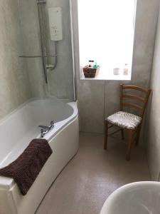 a bathroom with a tub and a chair and a shower at Forse of Nature in Latheron