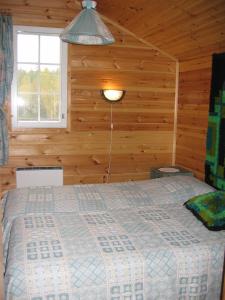 ein Schlafzimmer mit einem Bett in einer Holzwand in der Unterkunft Mäkelän Lomatuvat Cottages in Korkeakoski