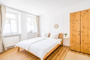 a white bedroom with a large bed and windows at Pension Herheinspaziert in Bad Breisig
