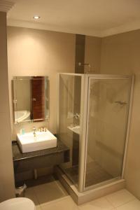 a bathroom with a sink and a shower at Oasis Hotel in Mokopane