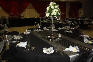 a set of tables with black table cloth and white flowers at Oasis Hotel in Mokopane