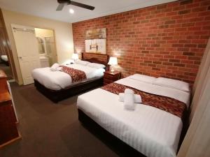 a hotel room with two beds and two lamps at Aussie Rest Motel in Cessnock