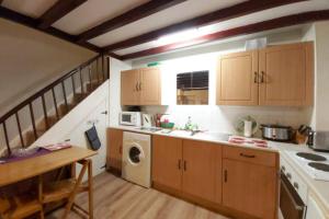 a kitchen with a sink and a washing machine at Self Catering Cottage in Talsarnau