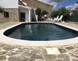 una piscina en un patio con mesa y sillas en Casadaldeiadalmofala, en Almofala