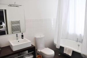 a white bathroom with a toilet and a sink at Carmelite Hotel in Aberdeen