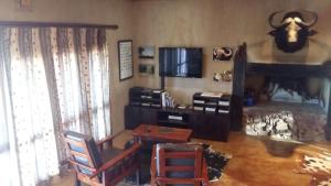 a living room with a television and a table and chairs at Gannabos Guest House in Kleinvie