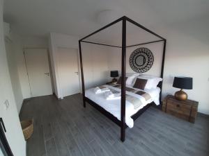 1 dormitorio con cama con dosel, sábanas y almohadas blancas en Cairnvillas - Villa Mar C38 Luxury Villa with Private Swimming Pool near Beach en Aljezur