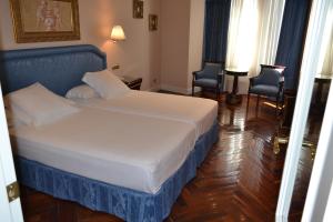 a hotel room with a bed and two chairs at Hotel Alameda Palace in Salamanca