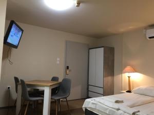 a room with a table and a bed and a tv at Hotel Unicornis in Eger