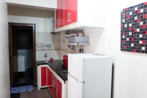 Il comprend une cuisine équipée de placards rouges et d'un réfrigérateur blanc. dans l'établissement Modern and Cozy Apartment, à Casablanca