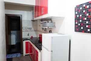 une cuisine avec des armoires rouges et un réfrigérateur blanc dans l'établissement Modern and Cozy Apartment, à Casablanca 1 autre photo