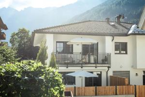 a white house with a balcony and two umbrellas at Oskar Apartments in Neustift im Stubaital