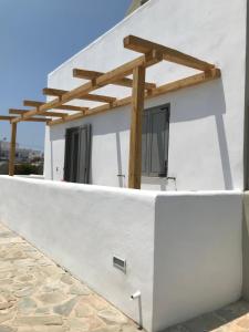 a white house with a wooden pergola on it at Thera Mare in Perissa