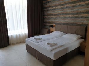 a bed in a bedroom with a wooden wall at Luxurious Studios Nani in Kranevo