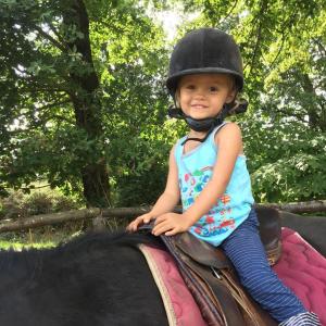 una niñita montada en la espalda de un caballo en Domaine des Pierres Jumelles-balade à cheval-chambre d'hôtes Mayenne, en Sainte-Gemmes-le-Robert