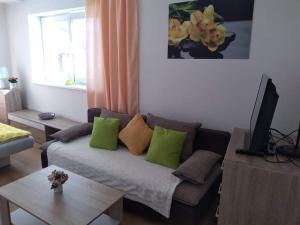 a living room with a couch with green pillows at Apartman NAOMI E12 in Nová Lesná