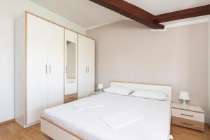 een witte slaapkamer met een wit bed en witte kasten bij Apartman Petelin in Novigrad Istria