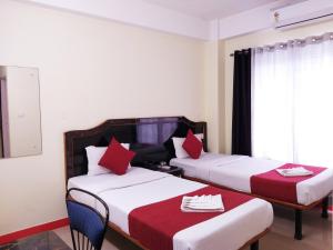 Habitación de hotel con 2 camas con almohadas rojas en HOTEL NILADRII GALAXY en Siliguri