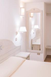 una camera bianca con specchio e letto di Colonna Beach Hotel a Marinella