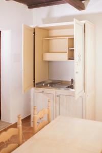 una cucina con mobili bianchi e tavolo di Colonna Beach Hotel Marinella a Marinella