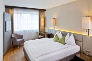 a hotel room with a large bed and a chair at Hotel Penz West in Innsbruck