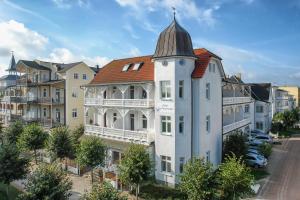 ein großes weißes Gebäude mit einem Turm auf einer Straße in der Unterkunft Strandhotel zur Promenade in Binz