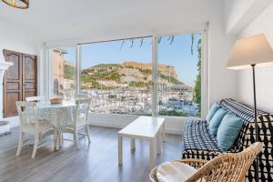 ein Wohnzimmer mit einem Tisch und Stühlen sowie einem großen Fenster in der Unterkunft Le Phare par Dodo-a-Cassis in Cassis