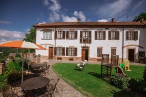 a house with tables and chairs and an umbrella at Il Pozzo Fiorito in Cossombrato