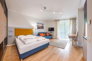 1 dormitorio con 1 cama grande y 1 sofá azul en Apartamenty Sun & Snow Leśne Zacisze en Świnoujście