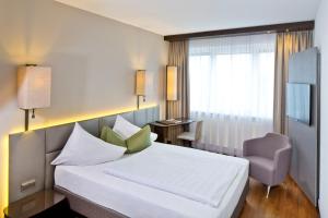 a hotel room with a bed and a chair at Hotel Penz West in Innsbruck