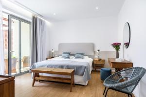 a white bedroom with a bed and a chair at Balance Hotel in Chania Town