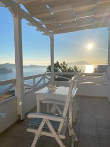 a table and a chair on a balcony with the sunset at Studios Betty in Plaka Milou