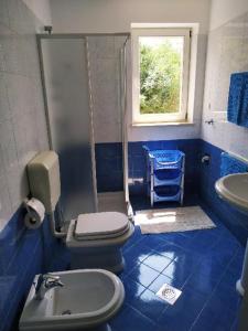 La salle de bains est pourvue de carrelage bleu, de toilettes et d'un lavabo. dans l'établissement APARTMANI INES RABAC, à Rabac
