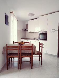 une cuisine avec une table et des chaises et une cuisine avec des placards blancs dans l'établissement APARTMANI INES RABAC, à Rabac