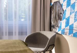 a chair sitting next to a window with a picture on the wall at Tryp by Wyndham Rosenheim in Rosenheim