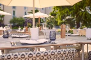 a wooden table with chairs and wine glasses at VILA VITA Rosenpark in Marburg an der Lahn