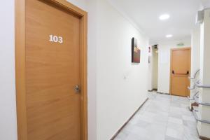 un corridoio con una porta di legno in un ospedale di Hostal la Campana a La Línea de la Concepción