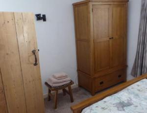 a bedroom with a bed and a wooden cabinet at Inglenook Cottage in Crediton