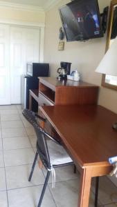 a wooden desk with a chair and a television on the wall at Lake Side Lodge in Lake Worth